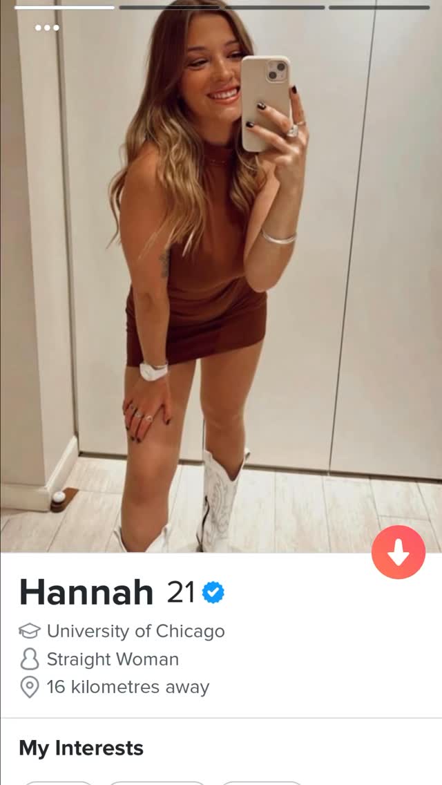 A woman smiles while taking a mirror selfie in a brown dress and white boots. The scene is lit with natural light, and a dating app profile is also displayed at the bottom of the image.