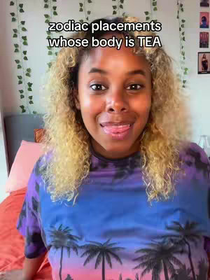 A woman with blonde curly hair and a blue and purple top sits on a bed with an orange bedspread. The background shows hints of a room with plants. Text overlays the image.