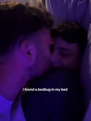 The image shows two males, faces close together, seemingly sharing an intimate moment. The lighting is low and dominated by a purple hue, which adds to the mood. Text overlayed reads 'I found a bedbug in my bed'.