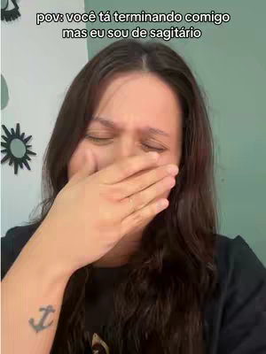 A woman is shown in a close-up, covering her mouth with her hand as if she is stifling a cry or reacting to something with strong emotion. She is looking down, and her eyes are closed. The text overlay reads: 'pov: você tá terminando comigo mas eu sou de sagitário'.