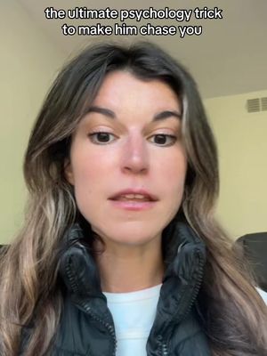 A woman with long brown hair and a black vest is centered in the frame. Text at the top states the video's topic. The background appears to be a neutral-colored wall.