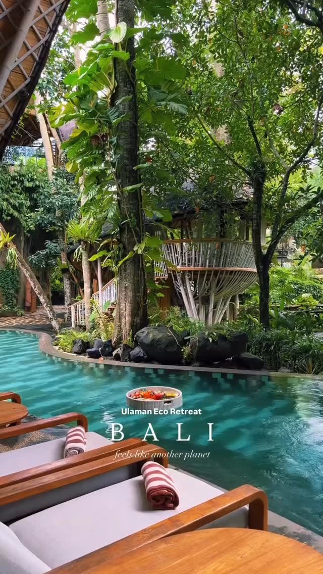 A lush, tropical scene featuring a swimming pool with turquoise water surrounded by abundant greenery and trees, suggesting a resort or retreat. Text overlays the image with the location name, destination and a tagline.