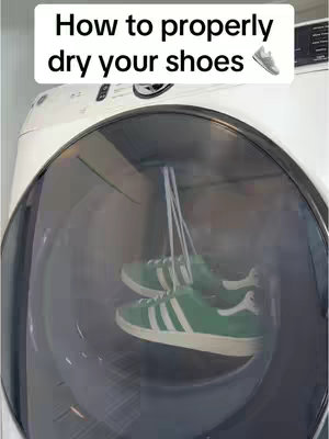 A washing machine with a transparent door revealing a pair of green shoes hanging inside. The text overlay reads 'How to properly dry your shoes'.