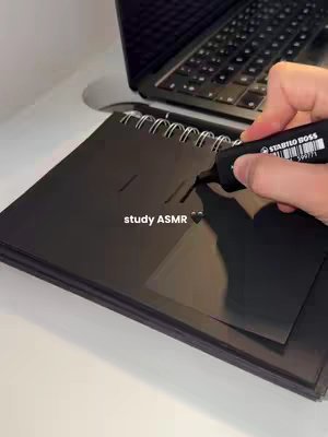 A hand with a black marker is writing on a black notepad. A laptop keyboard is visible in the background on the right side. The text "study ASMR" is placed at the bottom with a black heart emoji beside it.