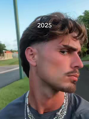 A young man with a fade haircut is shown in a profile view with the text "2025" overlaid. He is wearing a grey shirt and a silver chain.