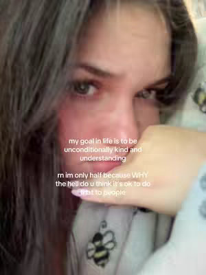 A close-up shot of a young woman's face with long, dark hair framing her face. She has a slightly pensive or troubled expression, with one hand partially covering her mouth and cheek. Text overlays appear in white font, offering a juxtaposition of kind intentions and a frustrated tone.