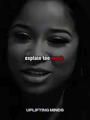 A monochrome close-up shows a woman's face with added text over her. The woman looks directly ahead with a slight smile. The image is primarily grayscale with the added text "explain too much" in white with the word "much" in red. The text "UPLIFTING MINDS" is at the bottom in white.