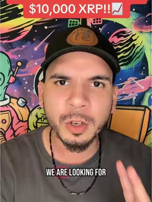 A man with short dark hair and a beard is the central focus. He wears a black cap with a logo, a dark gray t-shirt, and a black beaded necklace. The background includes a colorful, psychedelic mural with an alien figure.