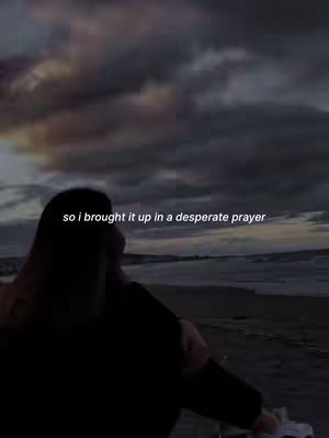 A woman stands with their back to the camera, facing a beach and cloudy sky. Text overlayed on the image reads, "so i brought it up in a desperate prayer".