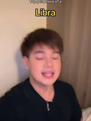 A young man with short brown hair is centered in the frame, his face showing an open mouth and slightly furrowed brow, suggesting he is speaking or reacting animatedly. Above him, text reads "Top pet peeve of a Libra" in a stylized font on a dark background. The background is a blurred, neutral color, possibly a wall.