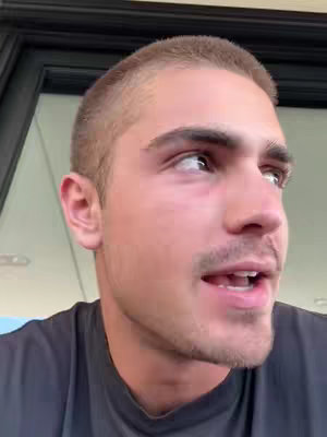 The cover image is a close-up of a young man's face, capturing his upper body. He has short, neatly styled hair, and is clean-shaven except for a slight mustache. The background is slightly out of focus, with a peek of a doorway or window frame visible. The man's expression appears engaged, looking upwards and slightly to the side, and his mouth is open as if he is mid-sentence.