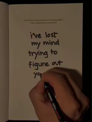 An image of a hand holding a black marker above a notebook. The notebook is open, with handwriting in the middle reading:
i've lost my mind
trying to
figure out
you