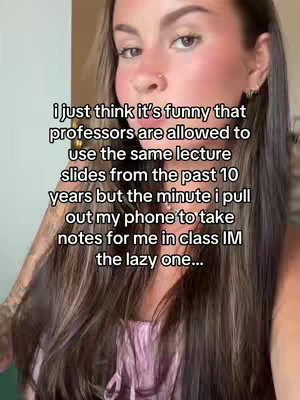 A selfie-style image featuring a young woman from the chest up. She has long, wavy brown hair and is wearing a light pink top. She has a nose ring and small hoop earrings. The text overlay is in white font and states, "i just think it's funny that professors are allowed to use the same lecture slides from the past 10 years but the minute i pull out my phone to take notes for me in class IM the lazy one..."