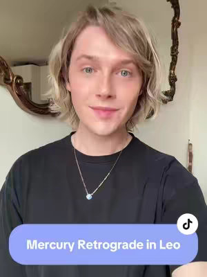 A well-lit, medium shot features a person with light-colored hair, positioned in front of a reflective surface, likely a mirror. The person, with fair skin and light eyes, is wearing a black t-shirt and a silver necklace. A text overlay is presented on a purple rounded rectangle. The overall composition is straightforward, with a neutral background that draws focus of the subject.