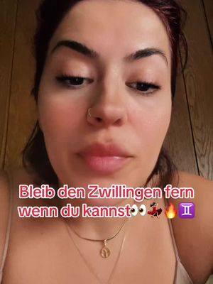 A close-up shot features a woman with brown hair and a fair complexion. She has a neutral expression with slightly parted lips. The overlay text in bright pink reads: 'Bleib den Zwillingen fern wenn du kannst' along with several emojis. A gold necklace with a pendant is visible.
