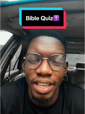 A man in a car, is the subject of a selfie-style photo. He has short, dark hair and is wearing clear-framed glasses. His mouth is slightly open, as if speaking. Above him, a bar with the words "Bible Quiz" is visible. The background shows the interior of a car.