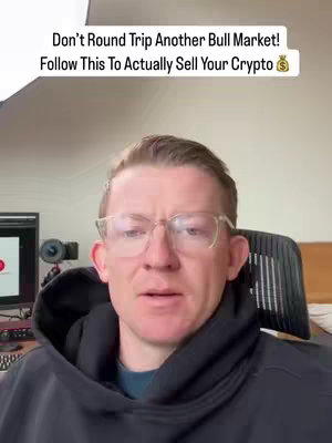 A man with fair skin and short reddish-brown hair wearing glasses and a black hoodie sits in front of a computer. Text on the image reads: Don't Round Trip Another Bull Market! Follow This To Actually Sell Your Crypto.