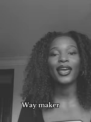 A black and white image featuring a woman with dark curly hair, smiling and looking slightly upwards. The text 'Way maker' is overlaid at the bottom.