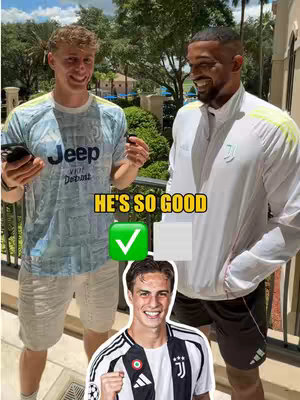 The image shows three men in a bright outdoor setting. Two are standing, smiling and looking towards the camera. The man on the left is wearing a light blue and white soccer jersey and light-colored shorts. He's holding a phone in his left hand. The other man is wearing a white jacket over a white shirt and black shorts. Underneath, in the bottom area another man is in the frame wearing a soccer jersey.
