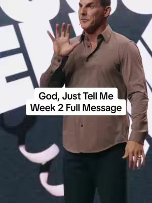 The image shows a man dressed in a button-down shirt addressing the camera, gesturing with his hand, likely delivering a sermon or presentation. The background appears to be a stage with white and black abstract design.