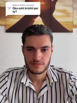 A man with dark hair and a short beard is centered in the frame, wearing a striped shirt. Behind him is a wall with a painted sunset and a heart shape formed by hands. A speech bubble is in the top left corner with text.