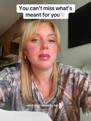 A woman with long blonde hair and a floral top looks directly at the camera, with text overlayed at the top. The background includes kitchen cabinets and a dark rectangle.