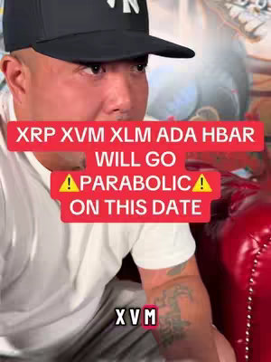 A man in a black baseball cap sits in front of a red booth. A red banner with white text reads "XRP XVM XLM ADA HBAR WILL GO PARABOLIC ON THIS DATE" and has yellow exclamation point symbols. The man's forearm with tattoo is visible. In the corner are the letters XVM.