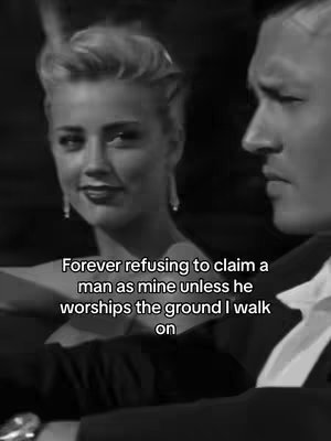 A black and white image shows a woman with blonde hair looking slightly to her right, smiling. Beside her is the profile of a man. Overlayed text is present at the bottom of the image.