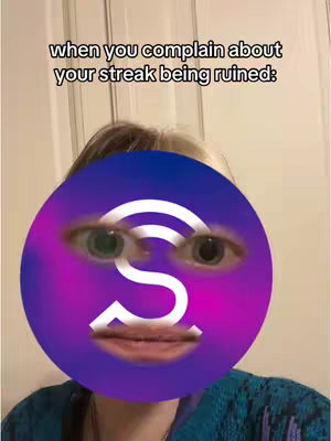 A selfie-style image featuring a person in the foreground with a large, circular digital illustration covering their face. The digital illustration has the appearance of a face with eyes and a mouth, and logo-like graphics. Background is a plain wall.
