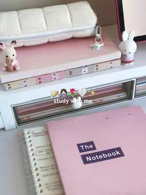 A desk setup with study materials, including notebooks, a pencil case, and decorative items like a bunny figurine and a small vase with a flower.
