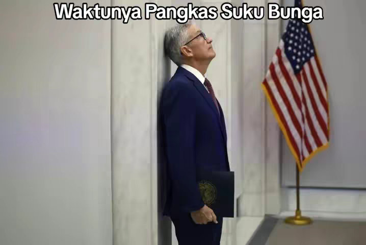 The image shows a man in a suit leaning against a wall, looking upwards pensively. The American flag is visible in the background.