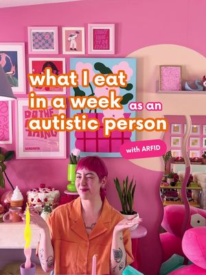 A woman with pink hair and an orange shirt stands in a colorful room with pink walls and artwork. Text overlays the image, stating what the video is about. Various objects are visible in the background, including framed artwork and decorative items.