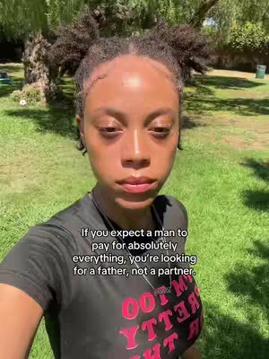 A selfie-style shot featuring a young woman outdoors in a grassy area. She is looking at the camera with a neutral expression. The background is blurred with green grass and trees. She is wearing a black shirt. The text overlay is in a white box.