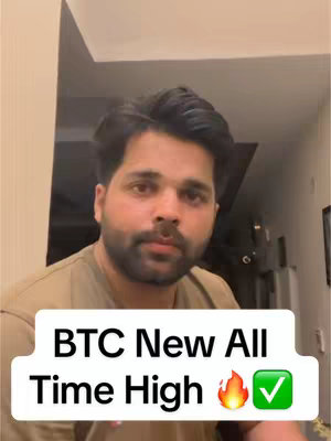 A man with dark hair and a beard is centered in the frame, looking towards the viewer. He wears a light-colored t-shirt. A white rectangle with the text “BTC New All Time High” is placed at the bottom of the image, along with a flame emoji and a check mark.