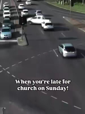 The image depicts a busy street scene with multiple cars moving on asphalt roads marked with white lines. The focus appears to be a silver car turning right while other cars continue straight. The sky is bright, suggesting daylight. Text overlayed at the bottom says, "When you're late for church on Sunday!"