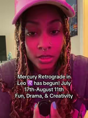 A selfie-style video cover focuses on a person from the chest up. The person is wearing a pink baseball cap and a dark purple shirt and has dark hair, styled in braids, and a nose ring. The background appears to be lit with warm, pinkish lighting. Overlayed text at the bottom of the frame displays information about the content focus and the Mercury Retrograde, including fun, drama, and creativity.