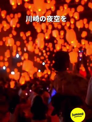 A night scene filled with numerous orange lanterns floating in the sky. The lanterns are the primary focus, filling the frame. In the foreground, crowds of people are faintly visible, with some holding up phones to capture the scene. The overall coloring is warm and inviting, with a mix of orange and red hues creating a festive atmosphere. Some lanterns are lit by the camera to the background, as well as people holding them, enhancing the effect. In the bottom right corner, there's a yellow circular Lemon8 logo.
