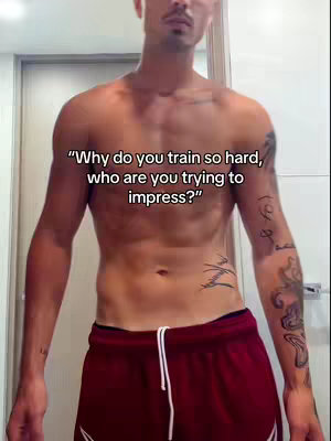 A shirtless man stands in a bathroom, showcasing a muscular physique. Red shorts are worn. The upper body is the focal point. Text overlays are superimposed.