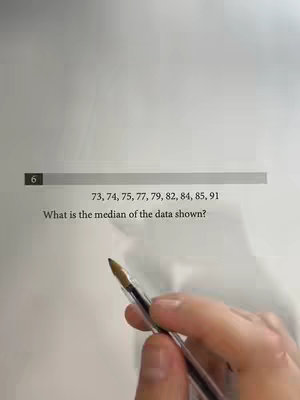 A close-up shot of a handwritten math problem on a piece of paper. A pen is in the foreground, pointing towards the problem. The lighting is bright and direct, and the composition is clean and focused.