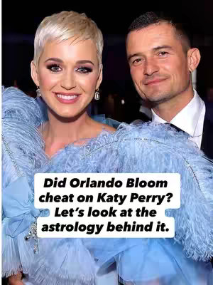 The cover image features Katy Perry and Orlando Bloom, smiling and posing together. Text overlayed on the image asks if Orlando cheated on Katy, with a call to look at the astrology behind the rumors. The composition uses natural lighting, possibly from a formal event.