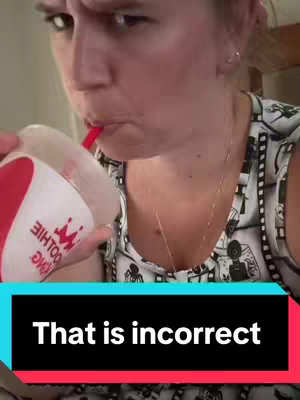 A woman is shown in a medium close-up, holding a smoothie cup to her mouth with a serious expression. The image is framed from the chest up, focusing on her face and the cup. The woman is fair-skinned. A text overlay appears at the bottom of the image: "That is incorrect." The Smoothie King cup is red with white font.