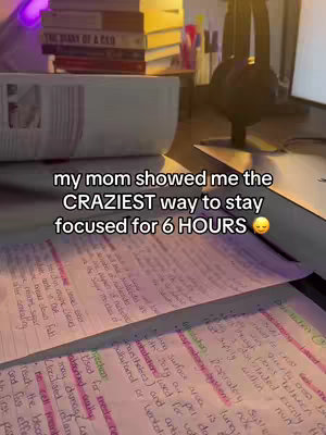 An overhead shot of a desk with notes and books. Pink highlighters are used on the notes. The hook is overlaid on the front of the notes. The lighting is dim and the color palette is warm-toned.