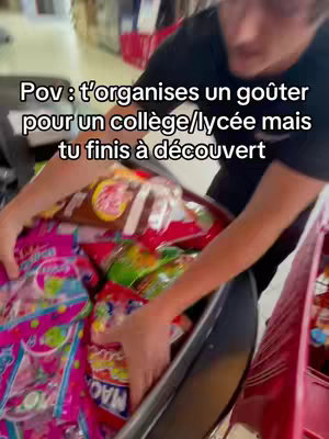 A person is holding open a shopping cart filled with colorful bags of candies and snacks. The image is taken from a slightly high angle, looking down into the cart. In the background, store shelves with red accents are visible.