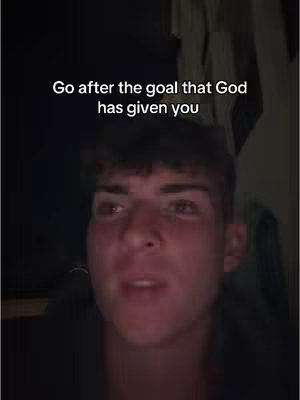 A medium shot features a young man looking directly at the camera, set against a dimly lit background. The text overlay at the top of the screen reads 'Go after the goal that God has given you'.