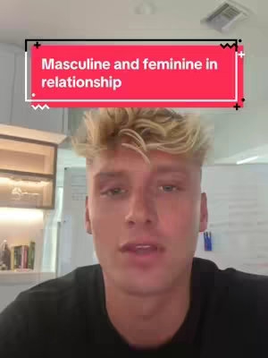 A young man with light blonde hair and a slightly open mouth is the focal point, framed from chest-up within a brightly lit indoor setting. Above his head, a rectangular text overlay reads 'Masculine and feminine in relationship' in white text against a red background. The text is bold and simple, the box design is slightly curved. The background appears to be a well-lit interior space, possibly an office or home setting, though details are blurred.