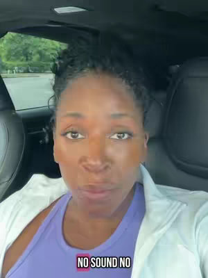 A woman with braided hair sits in the driver's seat of a car, facing the camera. She's wearing a purple tank top and a white jacket, and there is text overlayed on the image that says 'NO SOUND NO'. The background shows the car interior. A tree and building are seen throught the driver's side windows.
