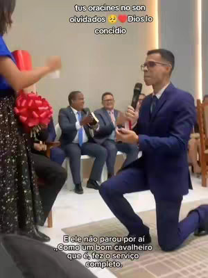 The cover image captures a moment during a church gathering. A man in a suit is kneeling, holding a microphone, with several other men in suits seated in the background. The woman in the side is holding a bouquet. Overlaid text in Spanish and Portuguese is present. The overall scene depicts a religious ceremony or related event.