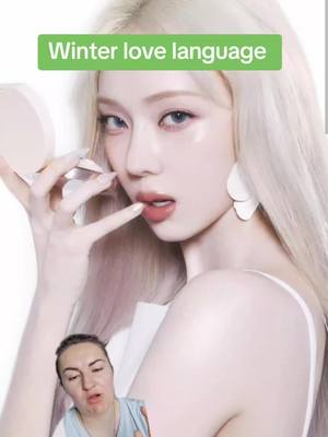 The cover image features two main figures: a portrait of a woman with pale skin, long light blonde hair, and striking makeup, and a smaller inset of a person with an open mouth, looking surprised. The top figure is the focus, holding a makeup compact to her hand with a finger to her lips. The image is highly stylized. A green rectangle with white text is positioned at the top.