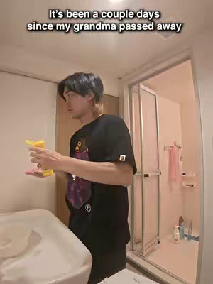 A man stands in a bathroom, holding a spray bottle. The bathroom is simply furnished with white walls, a shower, and a sink. Text overlays the image.