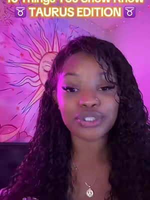 A woman with long, dark wavy hair is centered in the frame, facing the camera and speaking. Behind her is a purple tapestry featuring a sun design with radiating lines and what appears to be flowers. The text overlay is at the top of the image.